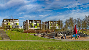 drei Mehrfamilienhäuser mit einer Grünfläche und Spielplatz